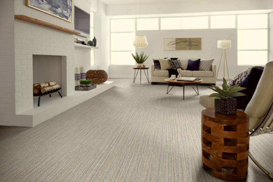 light grey patterned carpet in living room with cream couches and navy blue pillows